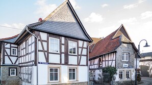 A traditional half-timbered building with a steeply pitched roof, a stone base, and a sign indicating it is a restaurant. - Vacation Home "Gästehaus Vis À Vis" with Mountain View, Shared Garden & Wi-Fi (Wallhausen)