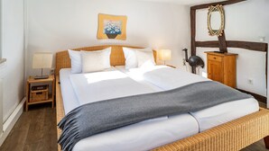 A bed with a headboard, a nightstand with a lamp, a wooden cabinet, and a wall-mounted mirror. - Vacation Home "Gästehaus Vis À Vis" with Mountain View, Shared Garden & Wi-Fi (Wallhausen)
