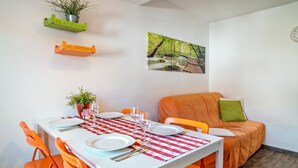 A dining area with a white table, orange chairs, and a red and white checkered tablecloth. - Holiday Apartment "4" with Mountain View, Shared Garden & Wi-Fi (Wallhausen)
