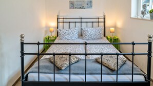 A bed with a metal frame, two pillows, and a bedside table with a lamp. - Holiday Apartment "4" with Mountain View, Shared Garden & Wi-Fi (Wallhausen)
