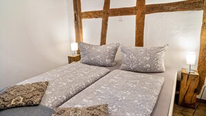 A double bed with patterned bedding, wooden headboard, bedside tables with lamps, and a power outlet. - Holiday Apartment "2" with Mountain View, Shared Garden & Wi-Fi (Wallhausen)