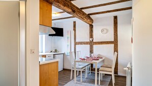 A modern kitchen with white cabinetry, a wooden ceiling, and a dining area with a white table and chairs. - Holiday Apartment "2" with Mountain View, Shared Garden & Wi-Fi (Wallhausen)