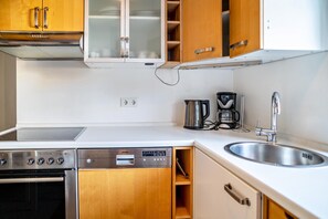 Une cuisine moderne avec des meubles en bois, un four encastré, un lave-vaisselle, une machine à café et un évier.