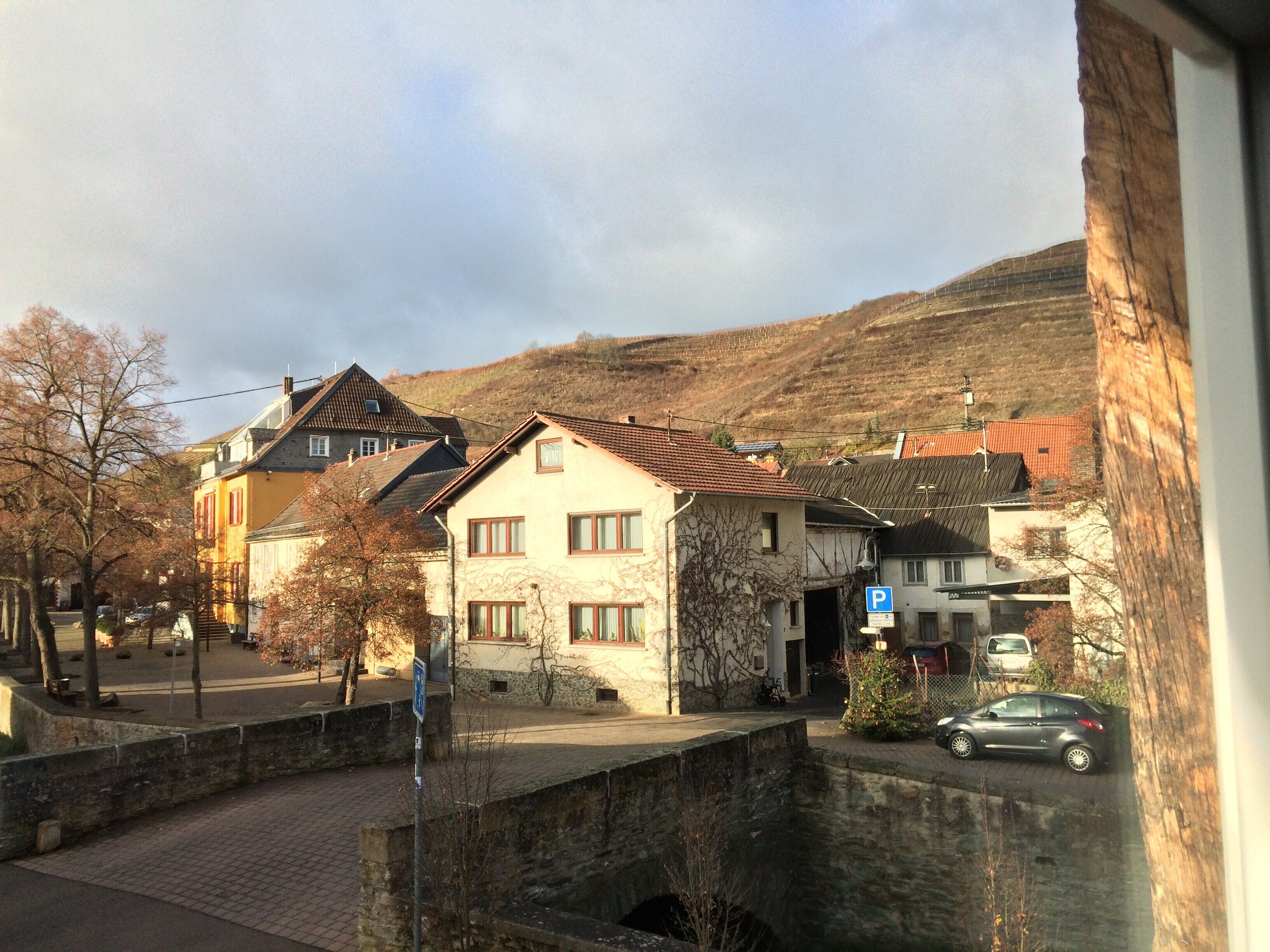 A street view with houses, a stone bridge, and a parking sign.