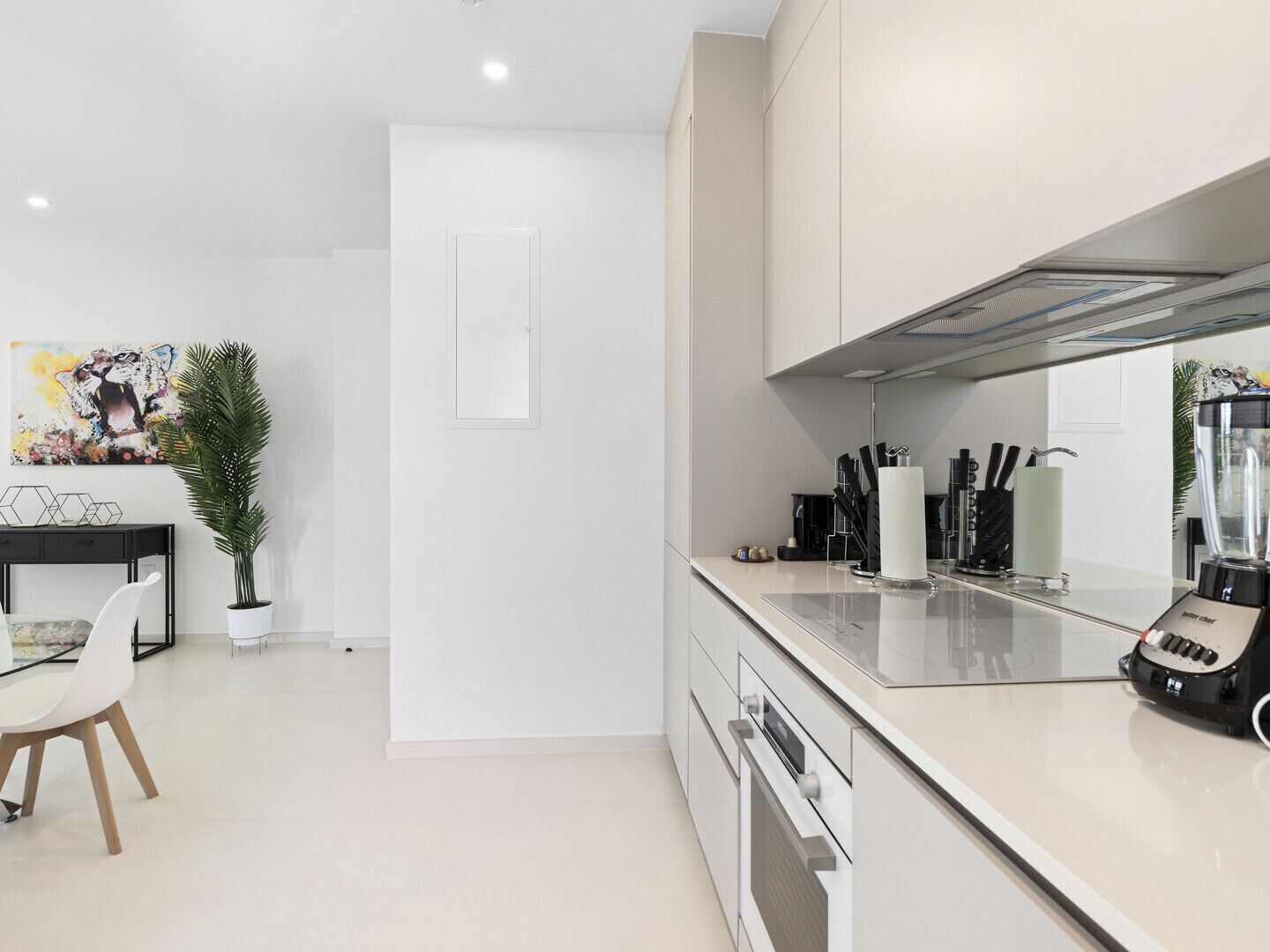 A modern kitchen with white cabinetry, a countertop, a coffee machine, and a blender.