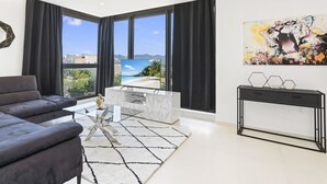 A modern living room with a sofa, a coffee table, and a view of a beach. - B-505 (Cupecoy)