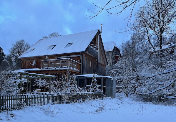 Eine Holzhütte mit geneigtem Dach, einem Balkon und einer Holzterrasse.