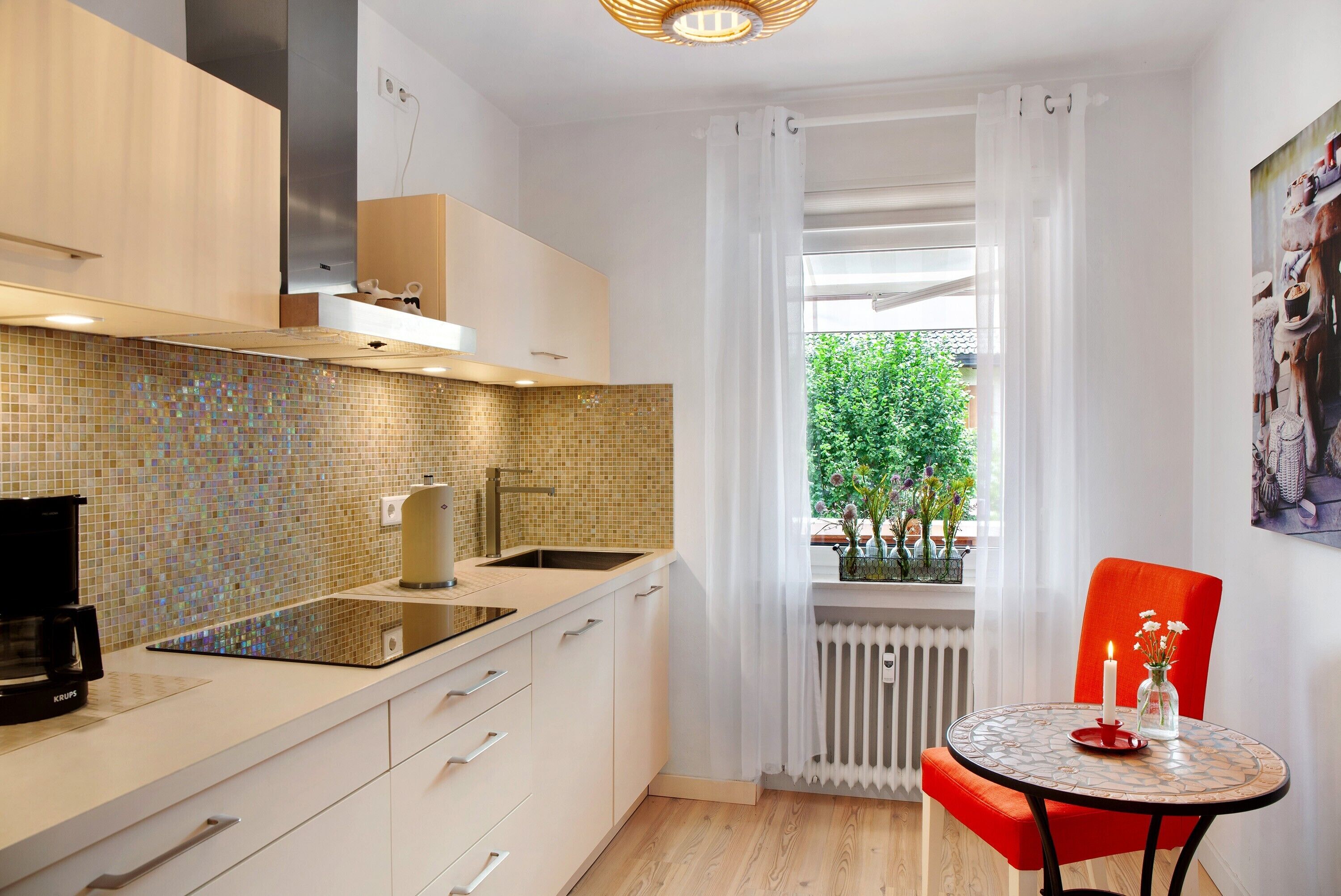Eine moderne Küche mit gefliestem Spritzschutz, einer Kaffeemaschine, einem Spülbecken und einem Fenster mit Blick auf Grünflächen.