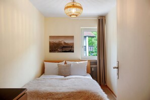 Una camera da letto con un letto, una finestra con tende, un termosifone e un quadro appeso al muro.