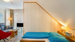 A bedroom with a bed, a desk, a chair, a TV, and a lamp. - Apartment 'Seestern - Wohnung 3' with Balcony and Wi-Fi (Norderney)