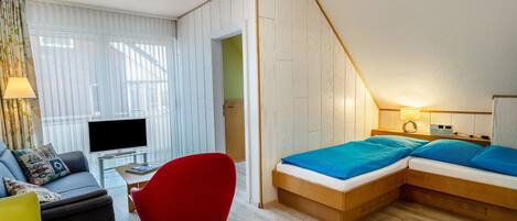 Une chambre d’hôtel moderne équipée d’un lit, d’une télévision, d’un bureau et d’un fauteuil rouge.