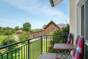 A balcony with a view of a wooden barn and solar panels, a table, and a chair. - Apartment 'Hackerhof' with Shared Terrace, Shared Garden and Wi-Fi (Bad Füssing)