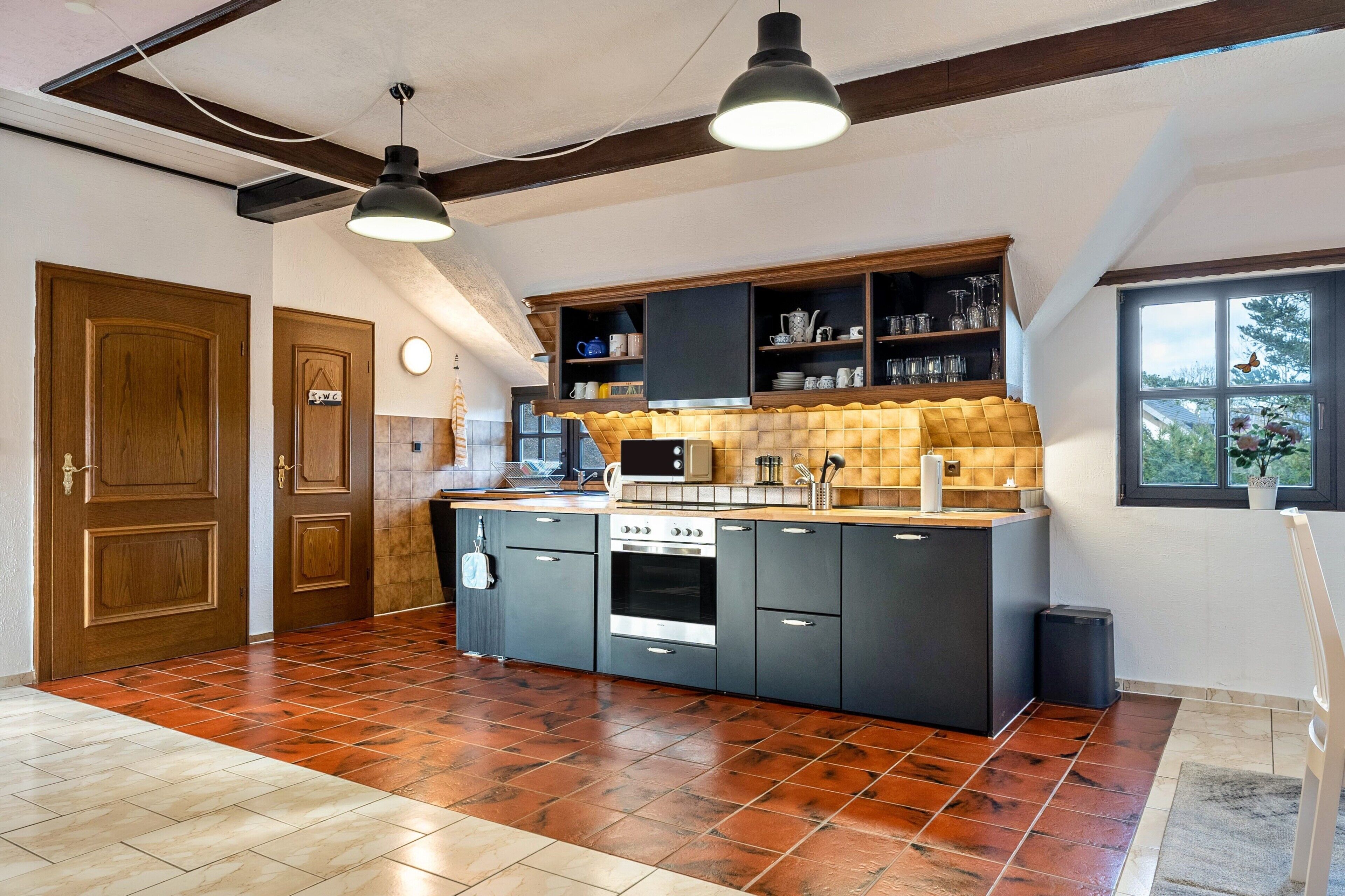 Una cocina con una isla central, armarios oscuros, una estufa y un ventanal con vistas.