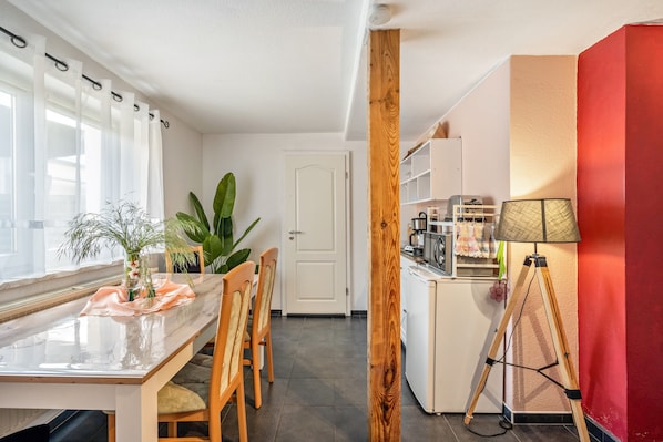 Eine moderne Küche mit einem Holztisch, Stühlen, einer Stehlampe und einem Kühlschrank.