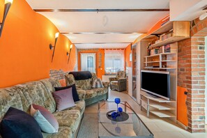 Un salon avec un canapé, un téléviseur et des étagères à livres.