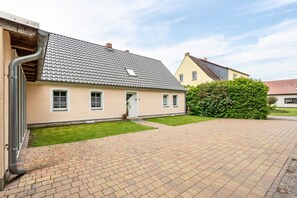 Un immeuble résidentiel avec un toit en tuiles, une allée pavée et une pelouse bien entretenue.
