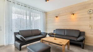 A modern living room with two black leather sofas, a wooden coffee table, and a white curtain. - Holiday Apartment 'Im Rosengarten 2' with Mountain View, Private Terrace and Wi-Fi (Zell am Harmersbach)