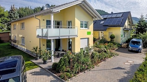 A two-story house with a balcony, solar panels, and a car parked in the driveway. - Holiday Apartment 'Im Rosengarten 2' with Mountain View, Private Terrace and Wi-Fi (Zell am Harmersbach)