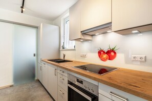 A modern kitchen with a wooden countertop, stainless steel appliances, and a window with a view. - Holiday Apartment 'Im Rosengarten 2' with Mountain View, Private Terrace and Wi-Fi (Zell am Harmersbach)