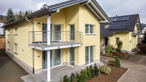 A two-story house with a balcony, solar panels, and a garden. - Holiday Apartment 'Im Rosengarten 2' with Mountain View, Private Terrace and Wi-Fi (Zell am Harmersbach)