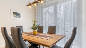 A dining area with a wooden table, black chairs, a potted plant, and a ceiling light fixture. - Holiday Apartment 'Im Rosengarten 2' with Mountain View, Private Terrace and Wi-Fi (Zell am Harmersbach)