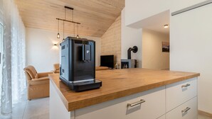 Una cocina moderna con cafetera, encimera de madera y armarios blancos.