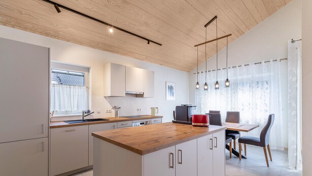Una cocina moderna con armarios de madera, una isla central e iluminación colgante.