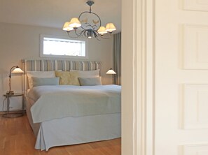 Quarto com cama, abajures, janela e lustre.