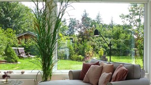 Een moderne woonkamer met een groot raam, een bank, een klein tafeltje en een plant in pot.