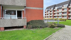 Ein Wohngebäude mit Ziegelverkleidung, einem Balkon und einem gepflasterten Weg.