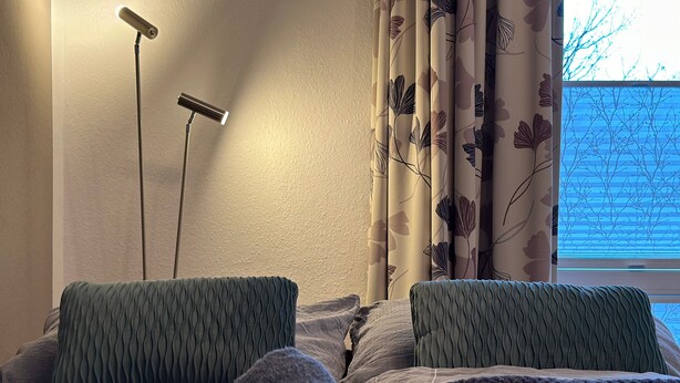 A bed with two pillows, a bedside lamp, and a window with curtains.