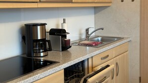 A kitchen with a microwave, coffee maker, toaster, and a sink with a faucet.