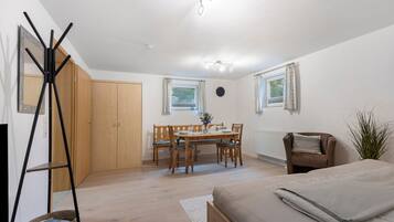 Une pièce comprenant un lit, une table à manger avec des chaises, un radiateur et une horloge au mur.