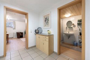 Cocina compacta con un mueble de madera, una tetera y una cafetera sobre la encimera.