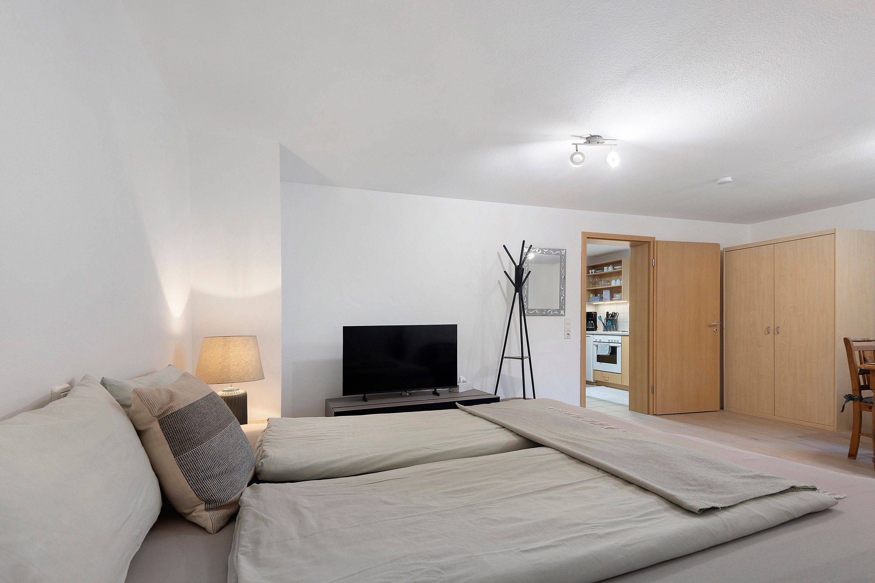 Ein Schlafzimmer mit einem Bett, einem Fernseher, einem Nachttisch, einer Lampe und einem Kleiderschrank.