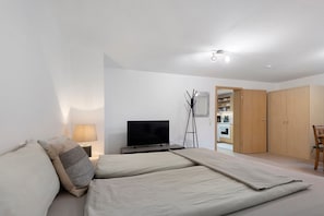 A bedroom with a bed, a TV, a bedside table, a lamp, and a wardrobe.