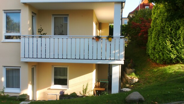 En toetagers bygning med balkon, vinduer og en have.