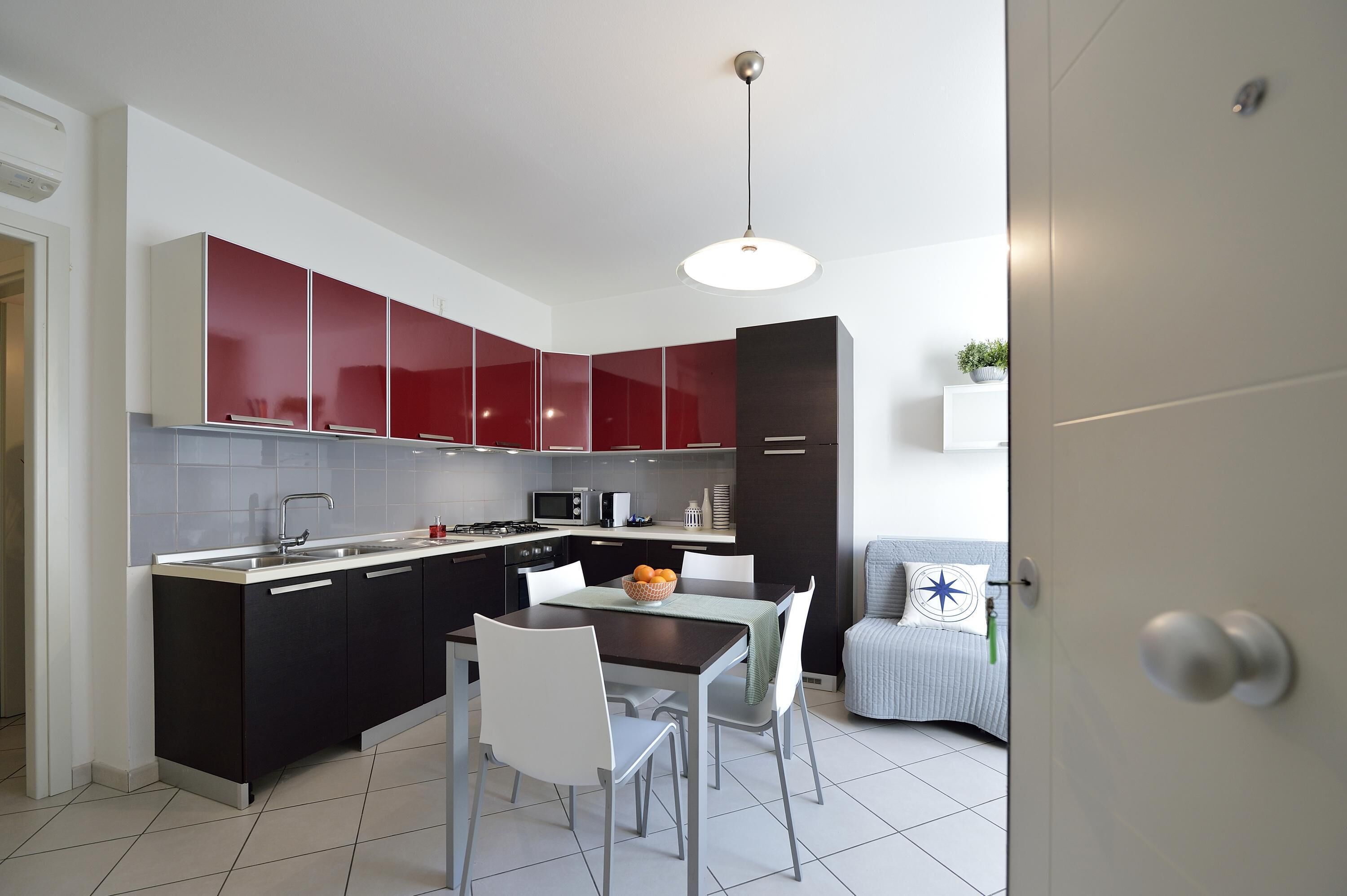 A modern kitchen with red cabinets, a dining table, and chairs.