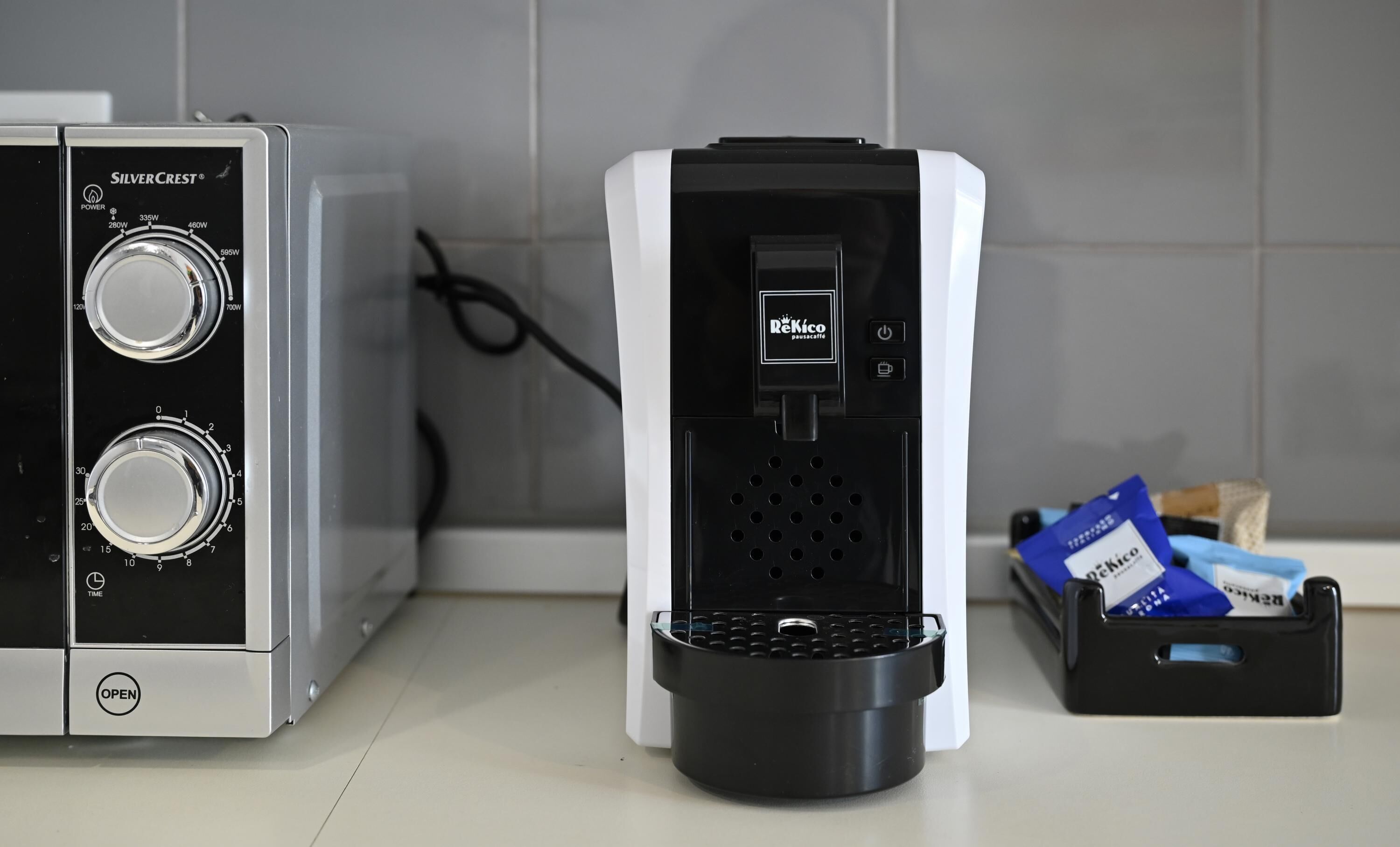 A coffee machine with a control panel, a water dispenser, and a coffee pod holder.