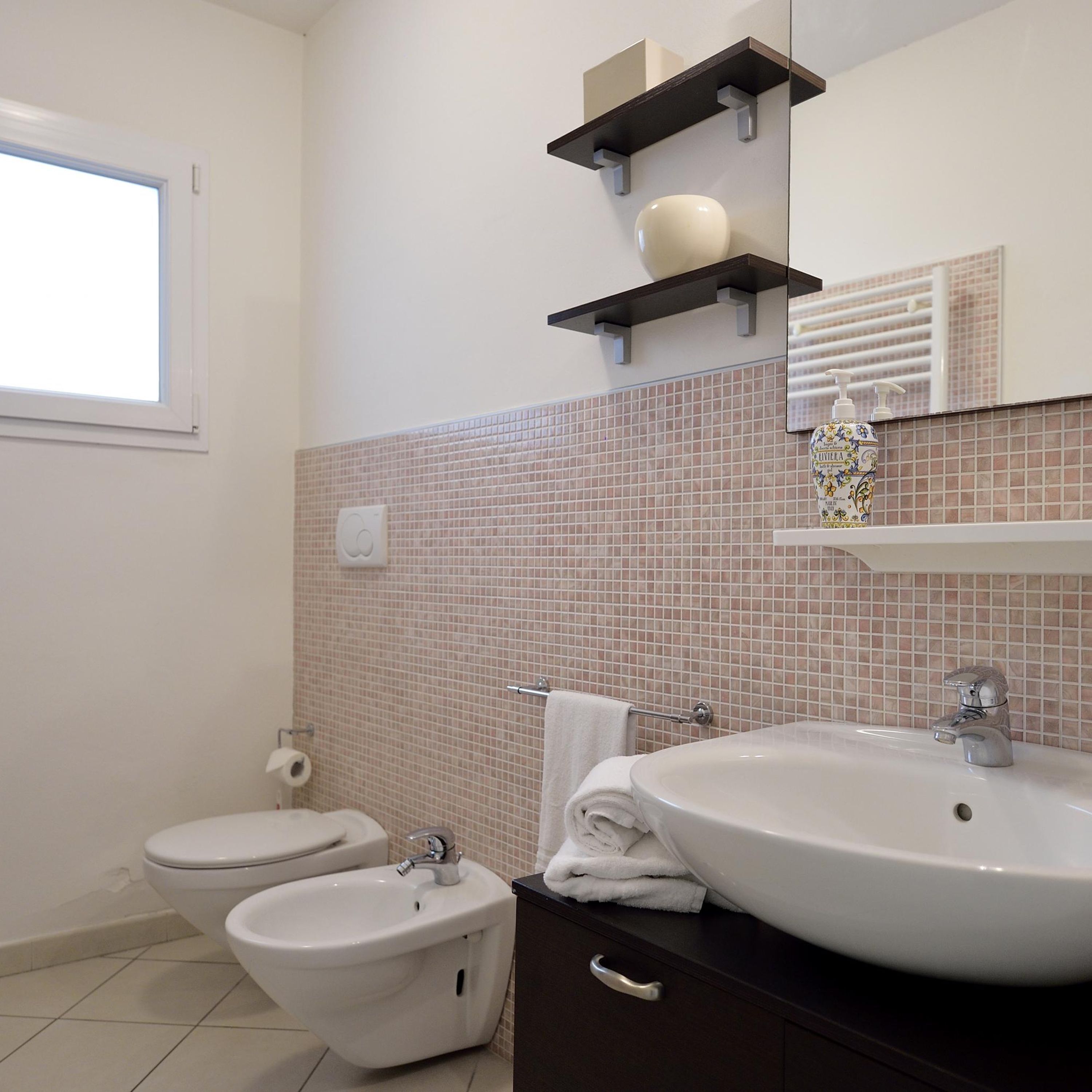 A modern bathroom with a toilet, bidet, and a sink with a mirror above.
