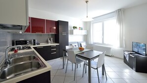 Une cuisine moderne avec un coin repas, un évier en acier inoxydable et un téléviseur à écran plat.