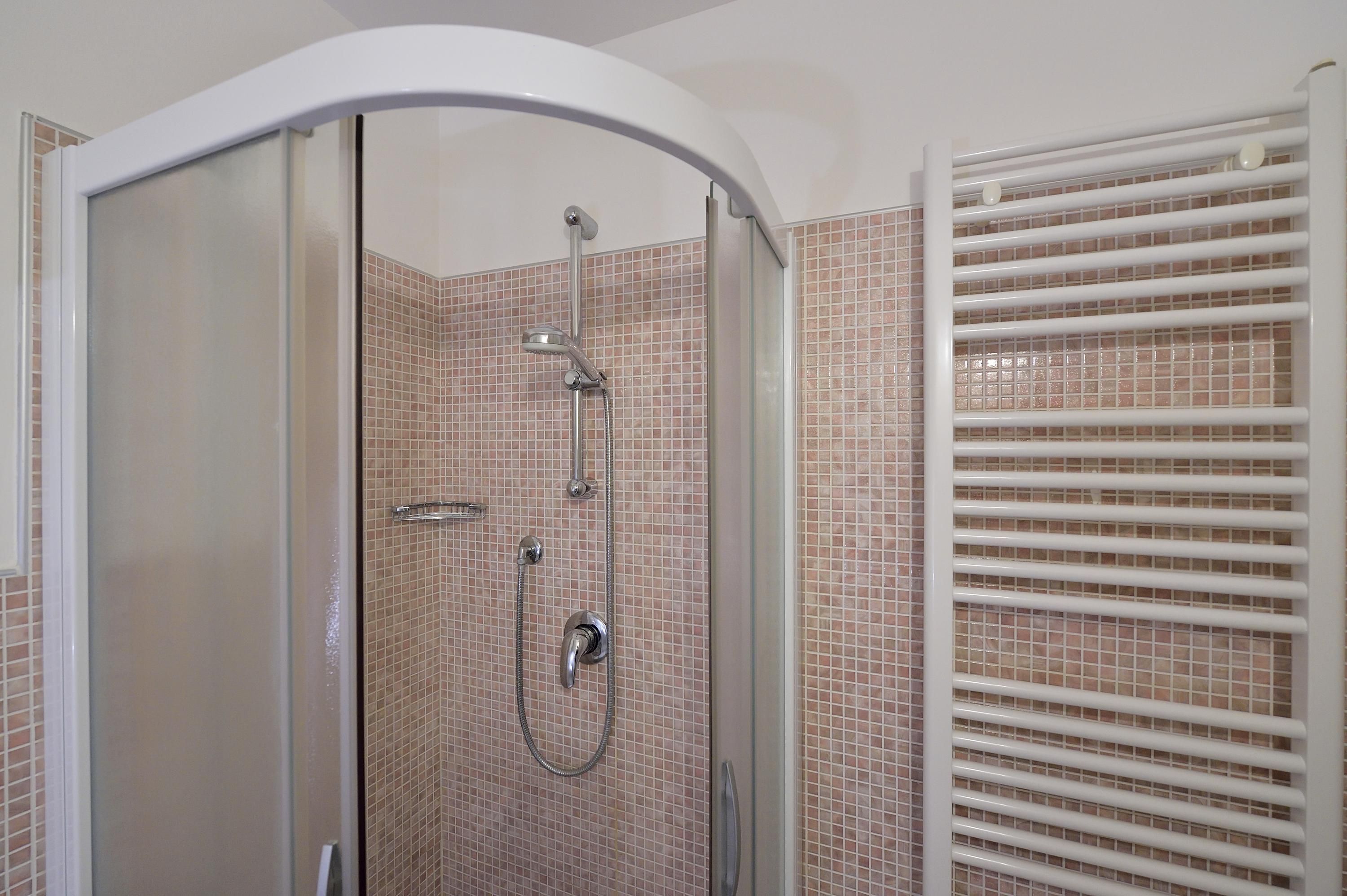 A walk-in shower with a glass door, tiled walls, and a white ceiling.