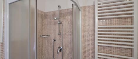 A walk-in shower with a glass door, tiled walls, and a white ceiling.
