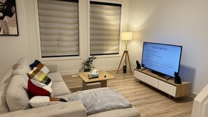A living room with a sofa, a coffee table, a TV, and a lamp.