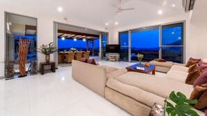 A modern living room with a large sofa, a flat-screen TV, and a dining area with a table and chairs. - Samui Summit villa (Koh Samui)