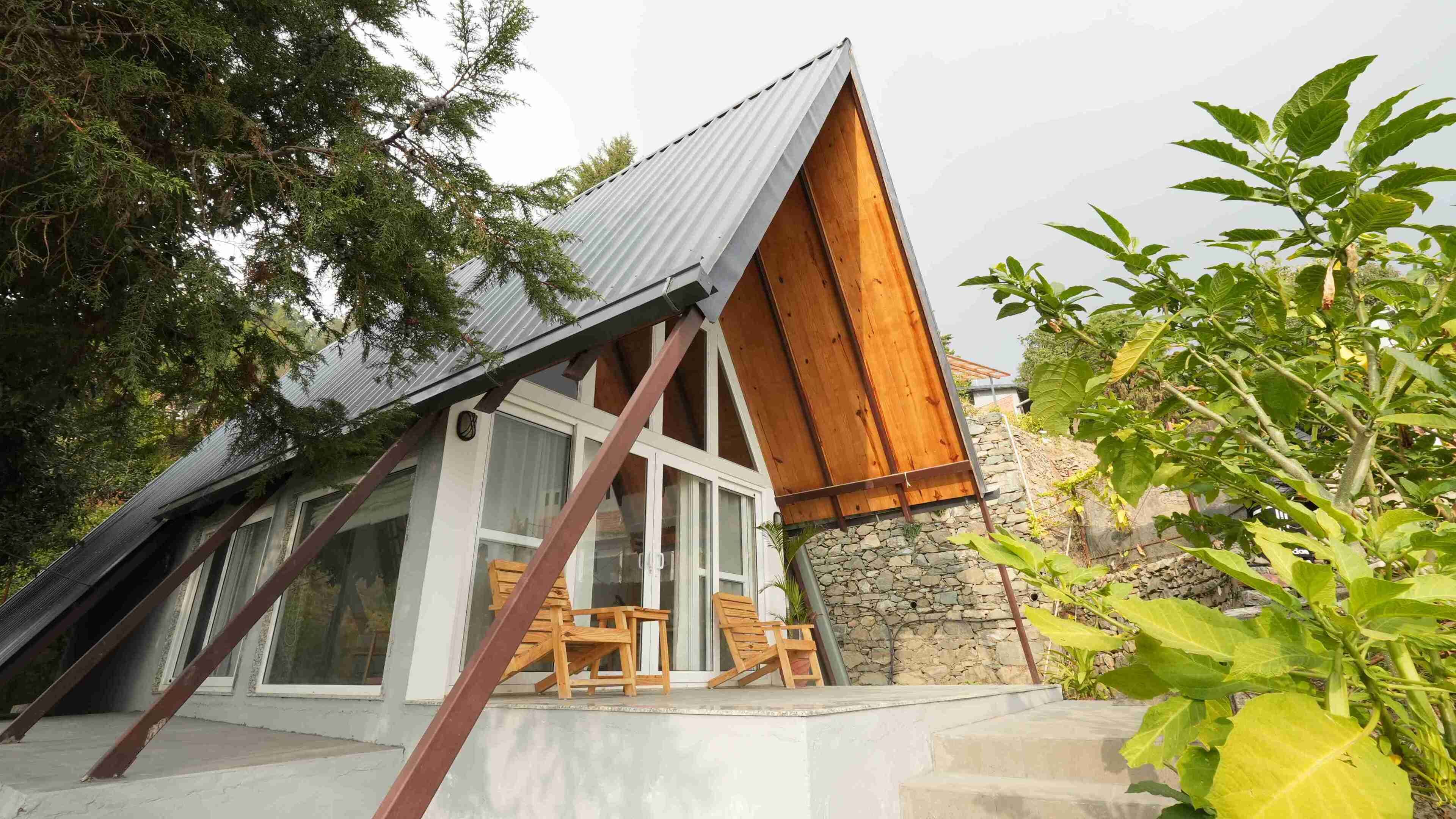 A modern house with a sloped roof, large windows, and a stone foundation.