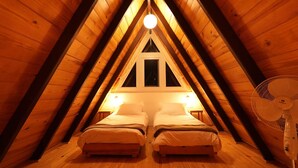 Une chambre mansardée agréable, avec deux lits, une fenêtre et un ventilateur.