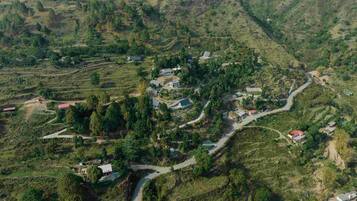 An aerial view of a rural village with terraced fields, scattered houses, and winding roads.