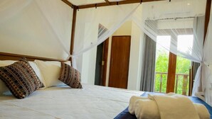 Una cama con dosel, almohadas estampadas y una toalla enrollada.