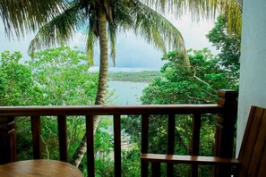 A wooden balcony with a view of a tropical landscape, including a body of water and dense greenery. - Secreat Mirage  (Mirissa)